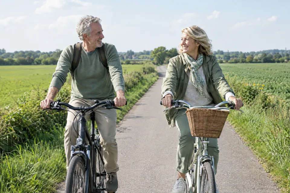 A couple in their sixties cycling along a country lane